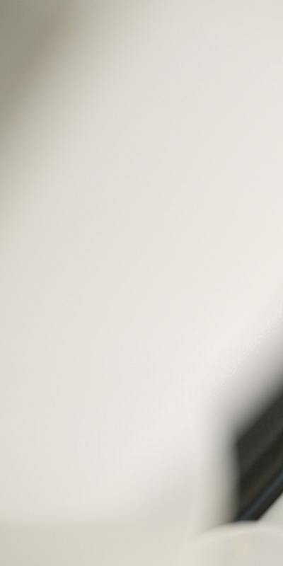 Close up of a pale beige wall with a soft diagonal shadow and a dark blurred edge in the lower right