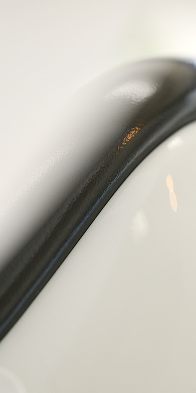 Close up of a curved white surface with a black edge seal along the seam