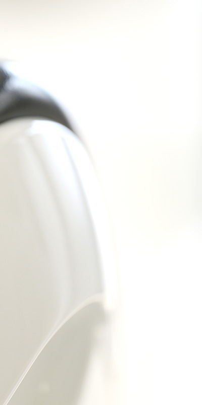 Close up of a glossy white curved surface likely ceramic against a bright soft focused background